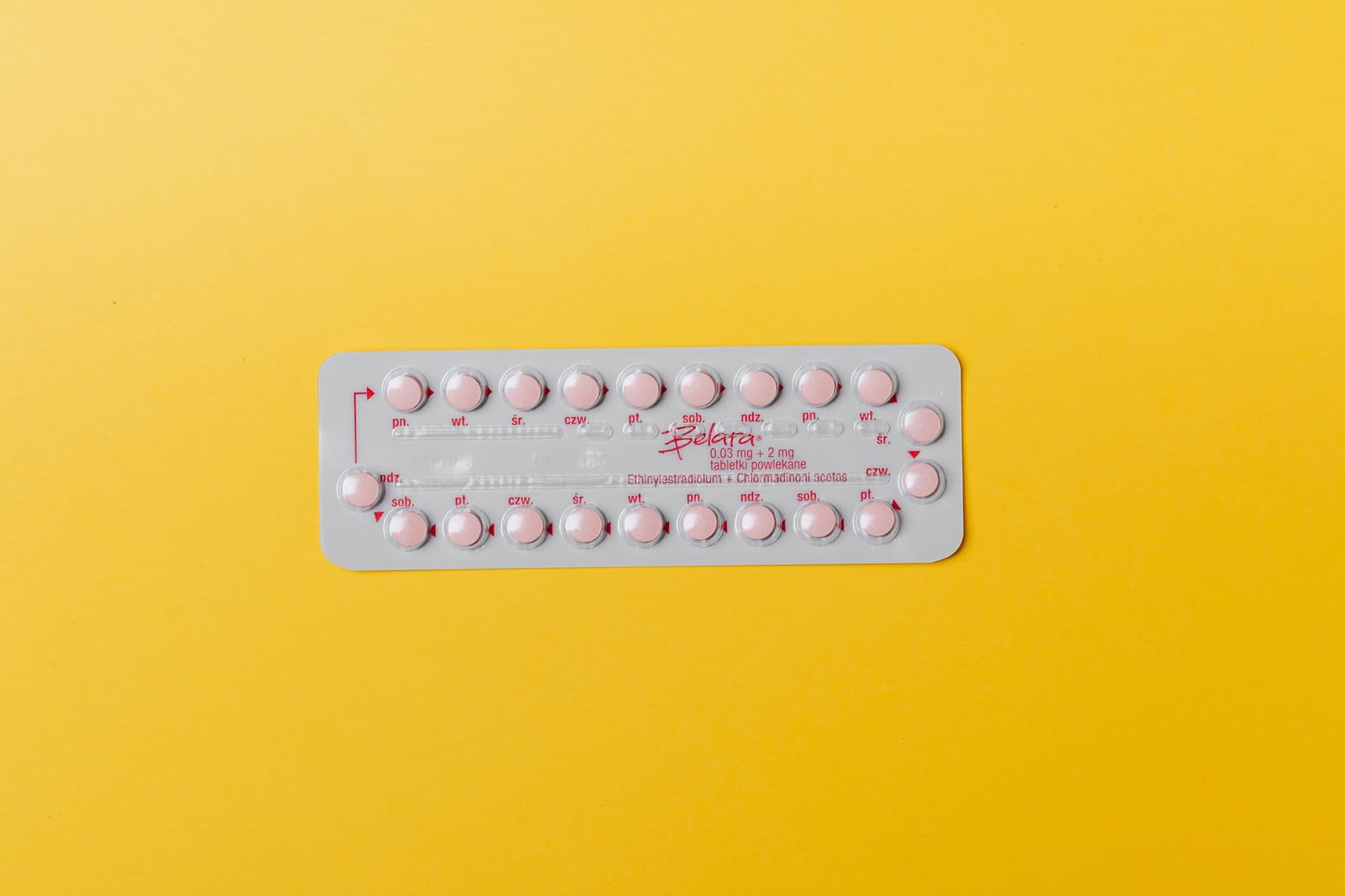 Close-up of a blister pack of pink pills on a vivid yellow background for medication concept.